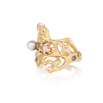 Yellow Gold ring with pearls and gemstones on a white background